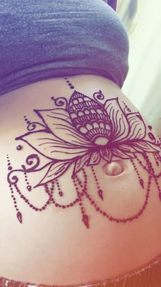 a woman's stomach with an intricate tattoo design on the side of her belly