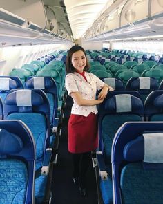 a woman standing in the aisle of an airplane with her arms crossed and looking at the camera