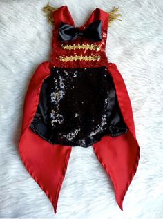 a red and black costume laying on top of a white furnishing covered floor