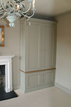 a living room with a fireplace, armoires and a chandelier hanging from the ceiling