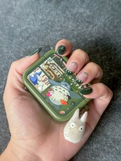 a hand holding a small green cell phone with animals on it