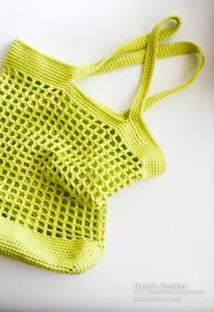 a crocheted yellow bag sitting on top of a white table next to a pair of scissors