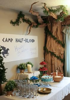 a table topped with cakes and desserts next to a sign that says camp half - blood