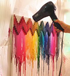 a person using a blow dryer to paint a rainbow heart design on a wall