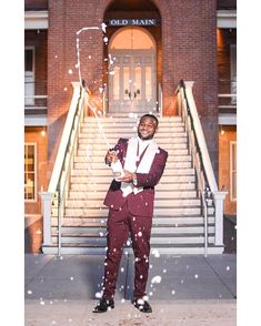 a man in a suit and bow tie standing on the sidewalk with snow falling from his hands