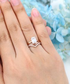 a woman's hand with two rings on it and blue flowers in the background