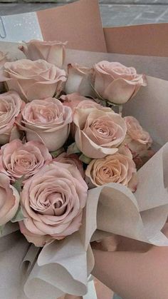 a bouquet of pink roses is wrapped in brown paper