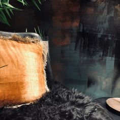 a black chair with a brown pillow on top of it next to a potted plant