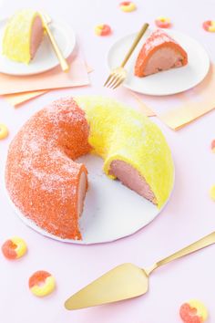 a yellow and pink cake on a white plate with one slice missing from the cake