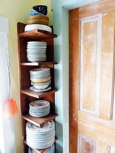 a stack of plates sitting on top of a wooden shelf in front of a door