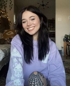 a woman sitting in front of a couch with tattoos on her arms and arm, smiling at the camera