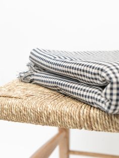 a black and white checkered blanket sitting on top of a wooden bench next to a wicker chair