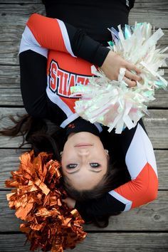 a cheerleader laying on the ground with her pom poms