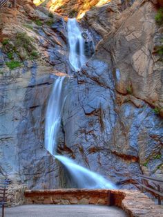 a waterfall is shown in the middle of a rocky area with stairs leading up to it