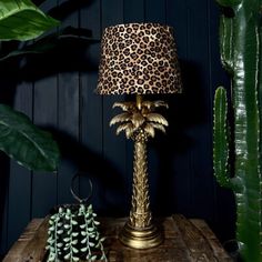 a lamp that is on top of a table next to a potted plant and a cactus