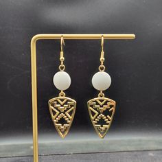 "These lightweight dangle earrings feature 30mm x 18mm gold-plated triangle charms with gorgeous boho Southwestern style cutouts dangling from 12mm matte white glass puffed coin beads. The triangles are made of a lead- and cadmium-free metal alloy. The ear wires are made of hypoallergenic gold-plated surgical steel, making these earrings safe for sensitive ears! They measure approximately 2.5 inches from the top of the ear wires to the bottom of the triangle charm and are fairly lightweight, weighing approximately 0.15 ounces each! Domestic shipping is always free here at Mayamadethis! When will my item ship? Every single item here at MayaMadeThis is made to order, meaning I make it especially for you after receiving your order. I even include a handwritten note in each shipment indicating Summer Wishlist, Wishlist 2024, Jewelry White, Southwestern Jewelry, Earrings White, Southwestern Style, Silver Spring, Glass Earrings, Sensitive Ears