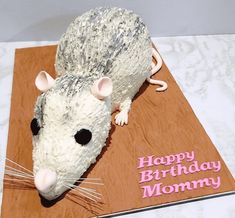 a cake shaped like a mouse on top of a wooden board with the words happy birthday mommy