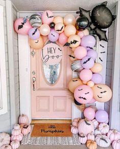 a pink door decorated with halloween balloons and pumpkins for the entrance to a house