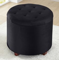 a black round ottoman sitting on top of a white rug