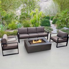 an outdoor fire pit surrounded by chairs and tables in the middle of a patio area