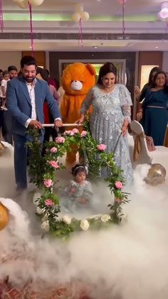 a man and woman standing in front of a cake with teddy bears on the top