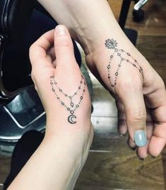 two people holding hands with tattoos on their fingers and one has a rosary tattoo on the wrist