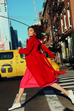 a woman in a red coat is crossing the street