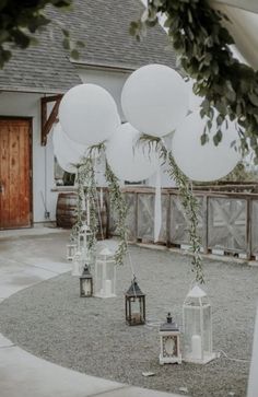 white balloons and lanterns are on the ground in front of an outdoor wedding ceremony venue