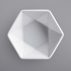 a white bowl sitting on top of a gray table next to a black and white wall