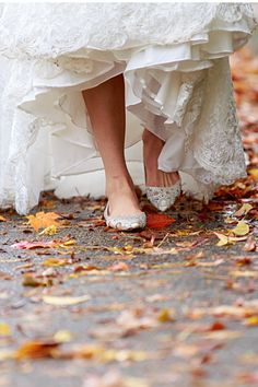 a bride and groom's wedding shoes on the ground with leaves all over them