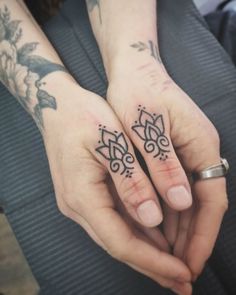 two people with matching tattoos on their hands holding each other's fingers and looking at the camera