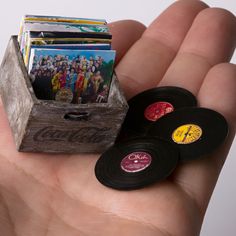 a hand holding a wooden box filled with vinyl records