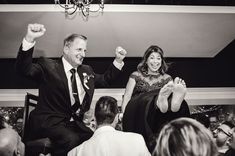 a man and woman are dancing together at a wedding reception with their arms in the air