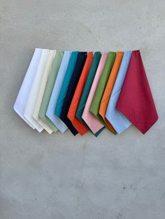 a bunch of different colored napkins hanging on the side of a wall with one folded in half