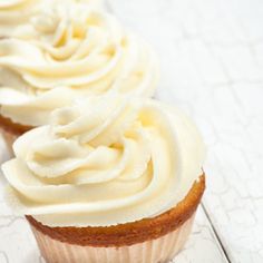 two cupcakes with white frosting sitting on top of a paper towel next to each other