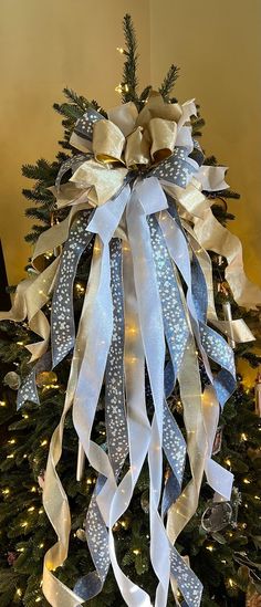 a christmas tree decorated with blue and white ribbons, bows and lights in the background