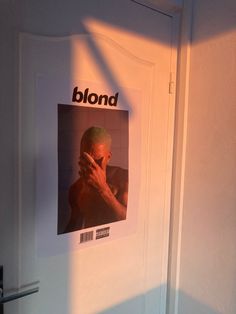 a photo of a man is projected on the wall next to a door with an ad for blond