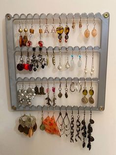 a wall mounted jewelry rack holds many pairs of earrings