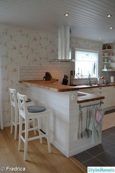 a kitchen with white cabinets and wooden counter tops next to a stove top oven in a small room