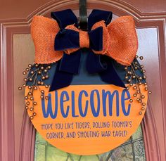 a welcome sign hanging on the front door to someone's home in orange and blue