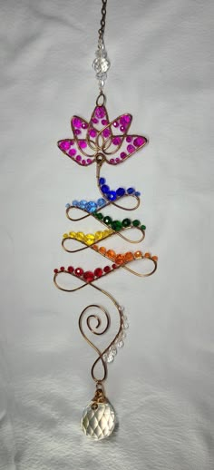 a multicolored metal wind chime hanging from a chain on a white background