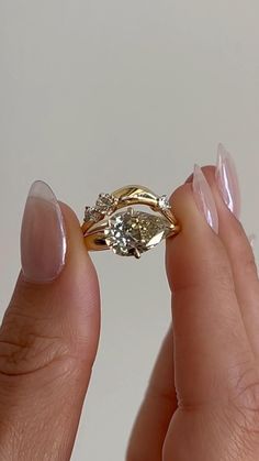 a woman's hand holding an engagement ring with two diamonds on the top and bottom