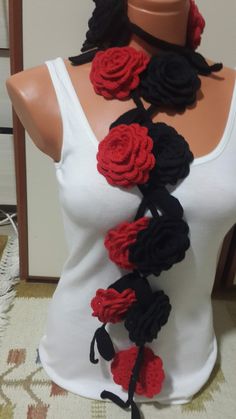 a woman wearing a white tank top with red and black crocheted flowers on it