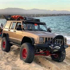 a jeep is parked on the beach by the water