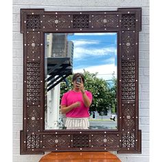 a woman taking a selfie in front of a mirror on a wooden bench with her cell phone