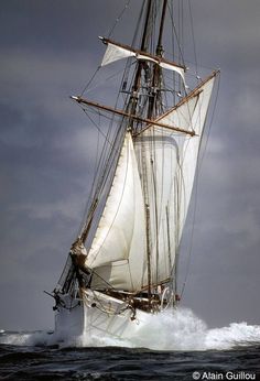 a sailboat sailing in the ocean on a cloudy day with white sails and masts