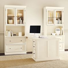 a desk with a computer on top of it next to a bookcase and cabinets