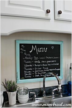 a kitchen with a chalkboard menu hanging on the wall and a potted plant next to it