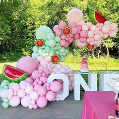 a table topped with lots of balloons and watermelon