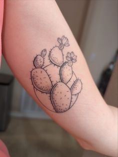 a woman's arm with a small cactus tattoo on the left side of her arm